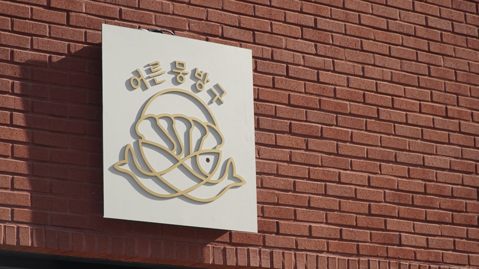측면에서 바라본 어른뭉방구 외부 간판과 붉은 벽돌 외벽
